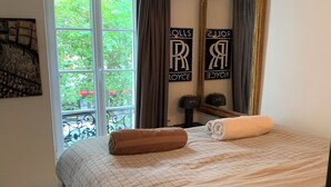 Un dormitorio con una cama, una ventana con cortinas, un espejo y una pared con una placa.