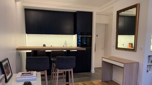 Una cocina moderna con armarios oscuros, encimera de madera y un pequeño comedor con dos sillas.