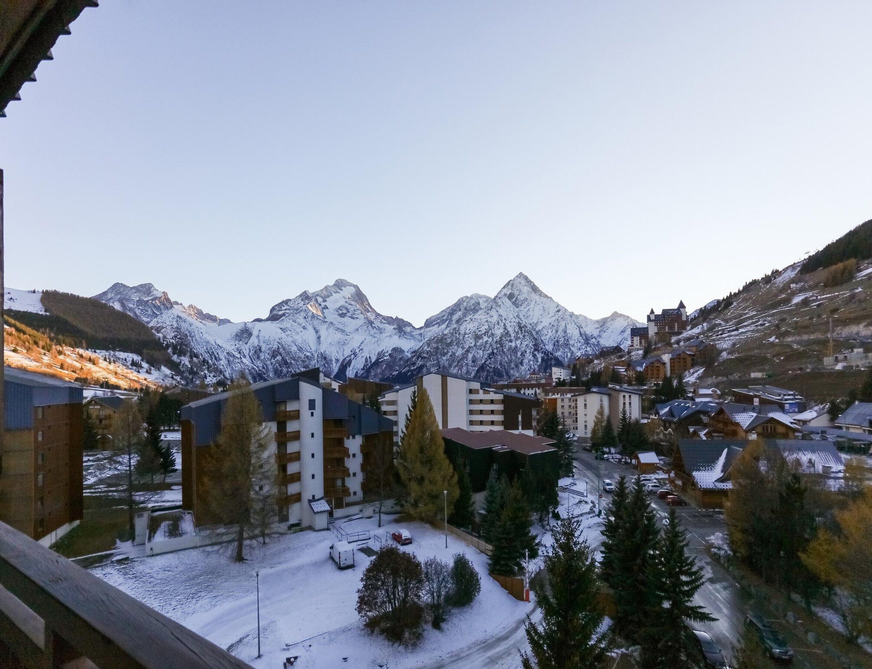 A snow-covered mountain town with buildings and a view of snow-capped peaks.