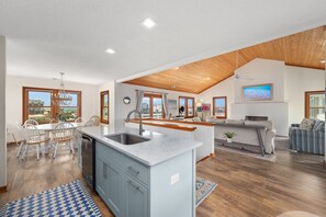 Una cocina amplia con una isla central, techo de madera y ventanas grandes.