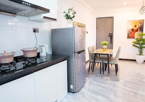 Une cuisine moderne dotée d’une cuisinière intégrée, d’un réfrigérateur en acier inoxydable et d’un coin repas avec une table et des chaises.