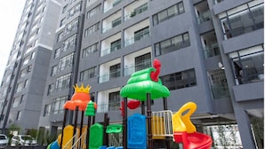 Un parque infantil con toboganes y estructuras de escalada frente a un edificio residencial de varios pisos.