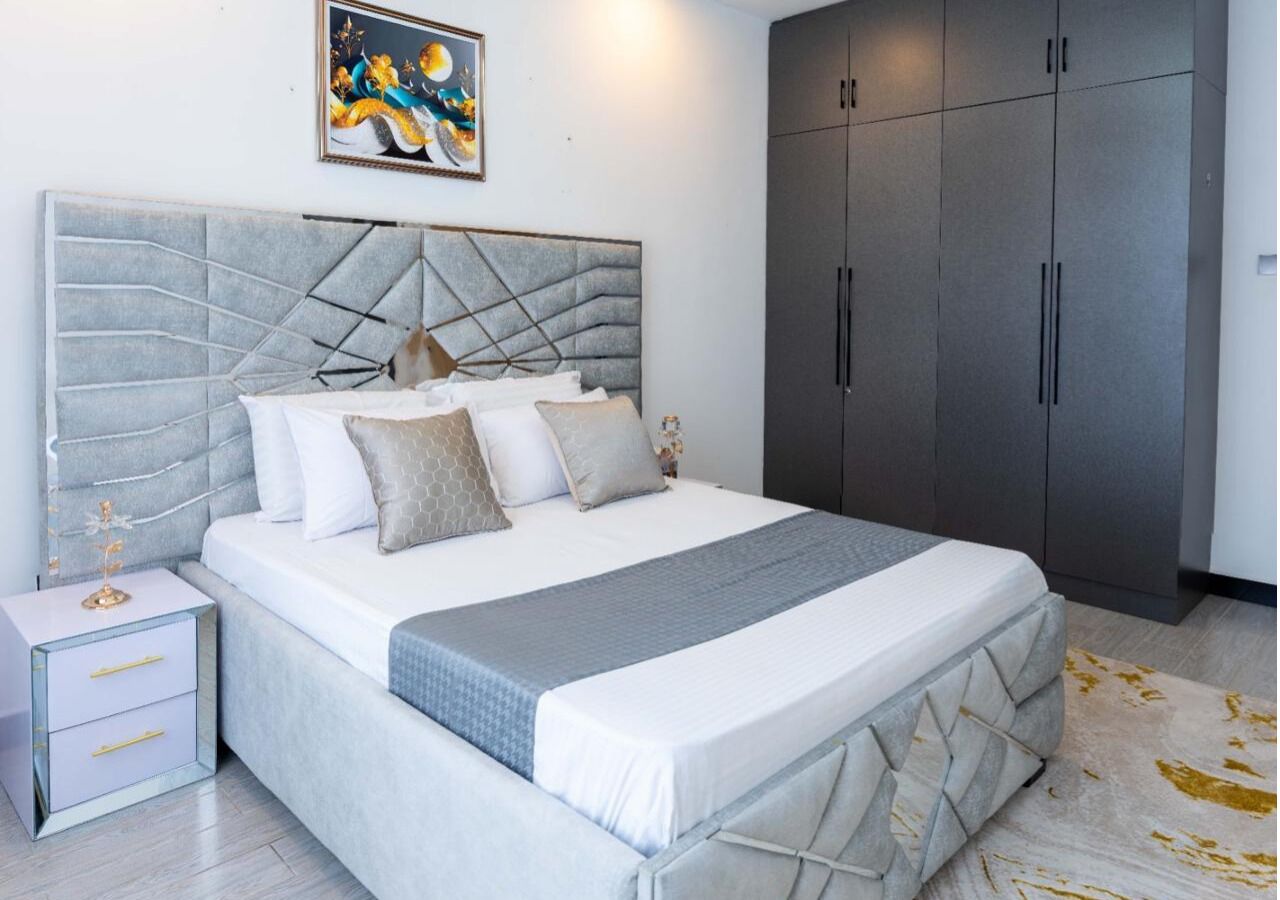 Un dormitorio con cama, mesita de noche, armario y un cuadro en la pared.
