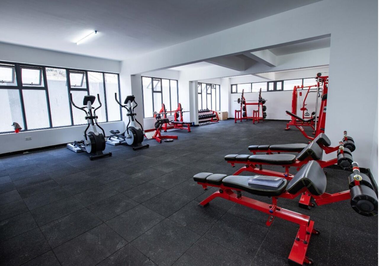 A gym with cardio machines, weightlifting equipment, and benches.