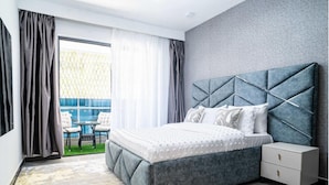 Un dormitorio con cama, mesita de noche, ventana con cortinas y vistas a un espacio exterior.