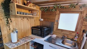 Eine kleine Küche mit Holzschränken, einer Mikrowelle, einem Spülbecken und einer Arbeitsplatte.