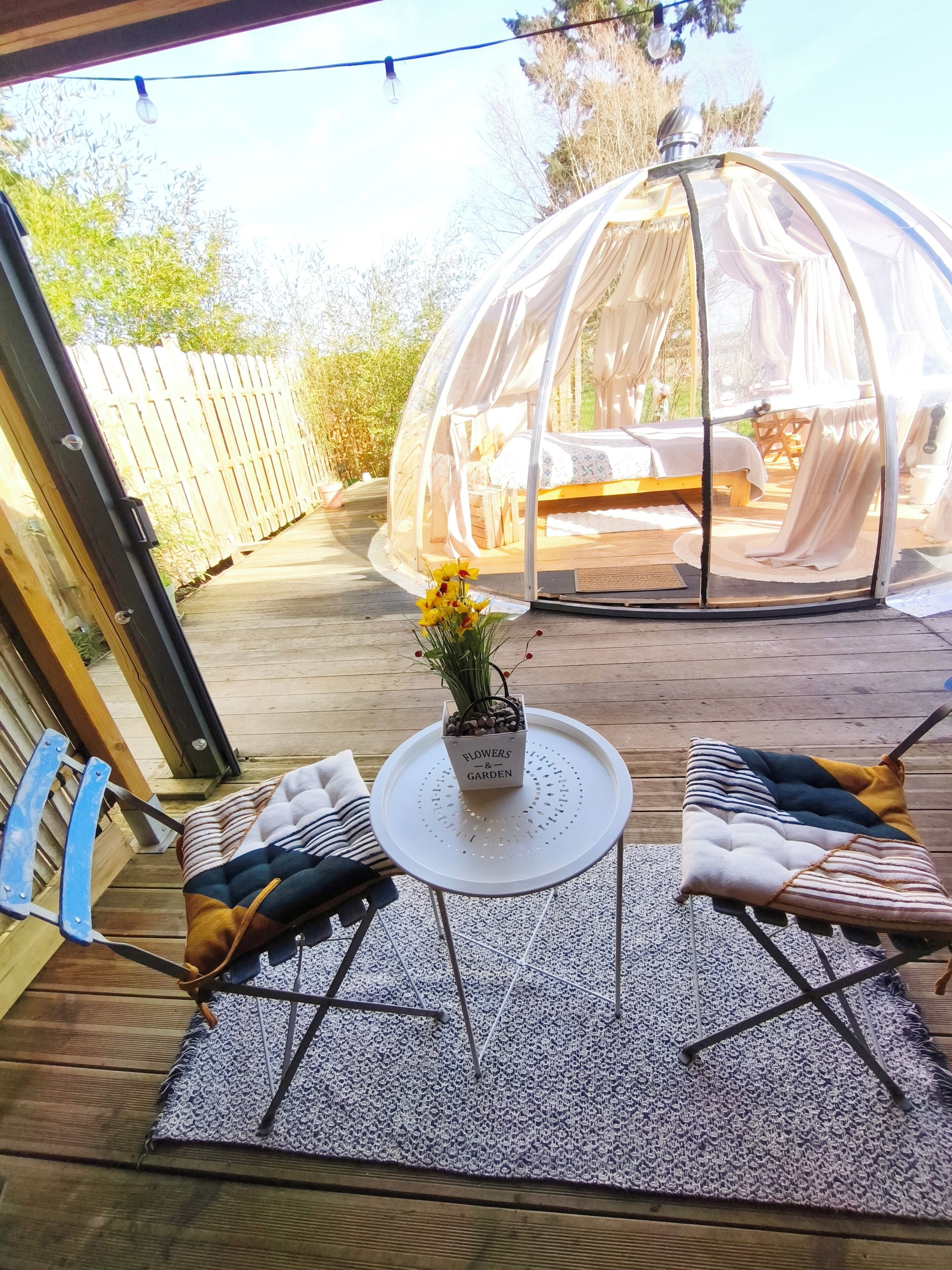Un espace extérieur accueillant, aménagé avec une table ronde, des chaises et une petite plante en pot.
