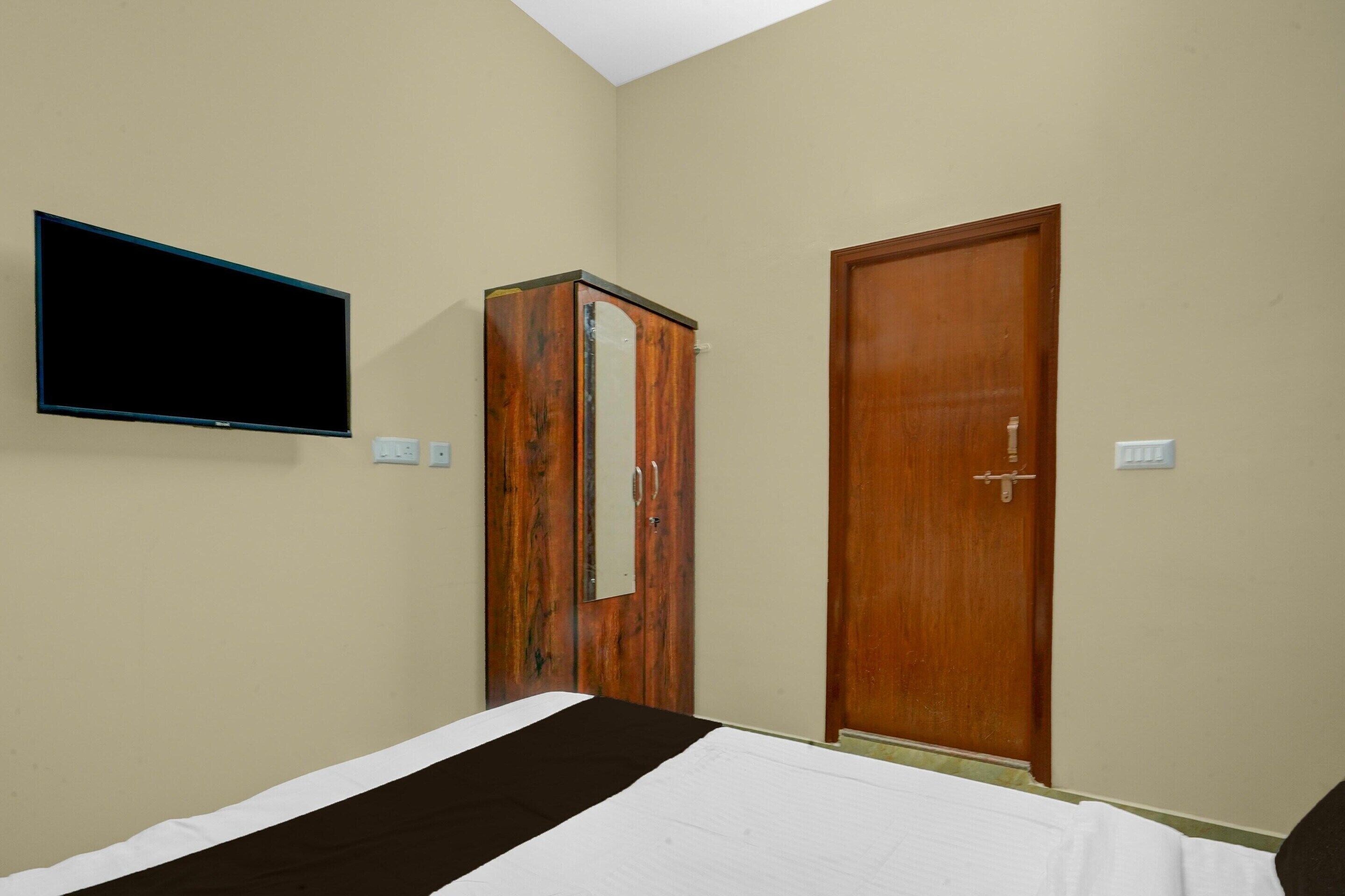 Een slaapkamer met een bed, een garderobe, een televisie en een deur.