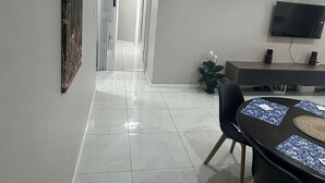A modern living room with a dining area, a TV mounted on the wall, and a hallway leading to another room. - Serene 3-bedroom House Rental in Secure Kempton Park Complex (Kempton Park)