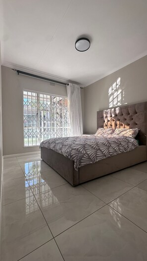 Ein Schlafzimmer mit einem großen Bett, einem Fenster mit Blick und einer Deckenleuchte.