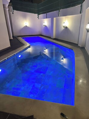 Une piscine dotée d’un éclairage bleu, entourée de murs équipés de luminaires.