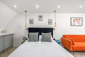 A bedroom with a bed, a nightstand, a dresser, and a sofa. - Modern Top Floor Studio in Putney SW15 | Sleeps 3 (London)