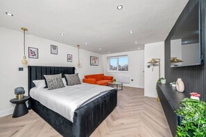 Une chambre à coucher moderne avec un grand lit, un canapé orange et une vue sur l’extérieur.