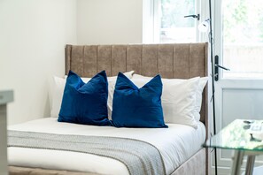 A bed with a headboard, two blue pillows, and a white pillow. - Modern Studio w/ Garden Access | Parking | SW16 #3 (London)