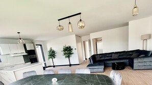 A modern living space with a dining table, chairs, a sofa, and a kitchen area. - New house Bretignolles sur Mer 1,5Km from the beach (Bretignolles-sur-Mer)