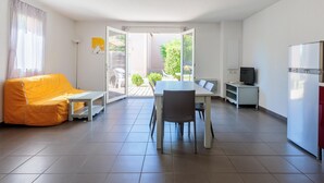 Un apartament modern amb zona de menjador, sofà, televisió i nevera.