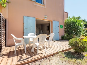 A wooden deck with a table and chairs, a building entrance with blue shutters, and a sign indicating a room number. - Duplex Holiday Home With Terrace (Aubignan)