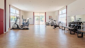 Una àmplia sala de gimnàstica amb màquines cardiovasculars, equipament de musculació i grans finestrals.