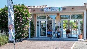 Entrada d'hotel amb un tauleller, portes de vidre i una petita zona de seients a l'aire lliure.