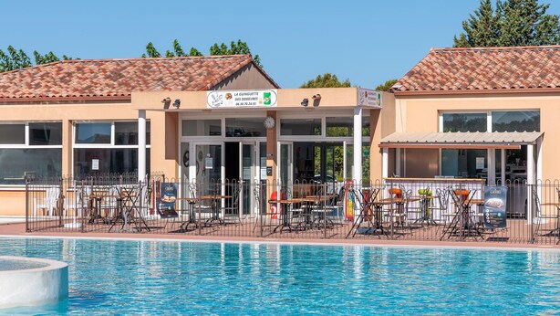 Zona de piscina amb mobiliari exterior i un edifici amb teulada d'aceràmica.