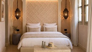 A bedroom with a large bed, two bedside tables, a nightstand, a decorative wall panel, and two hanging lanterns. - Maison Zamane (Marrakech)
