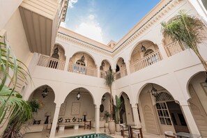 Un patio con arcos, zonas de estar y una piscina.