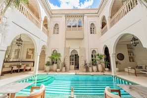 Ein Innenhof mit Swimmingpool, Kübelpflanzen und einer Sitzecke mit Tisch und Stühlen.