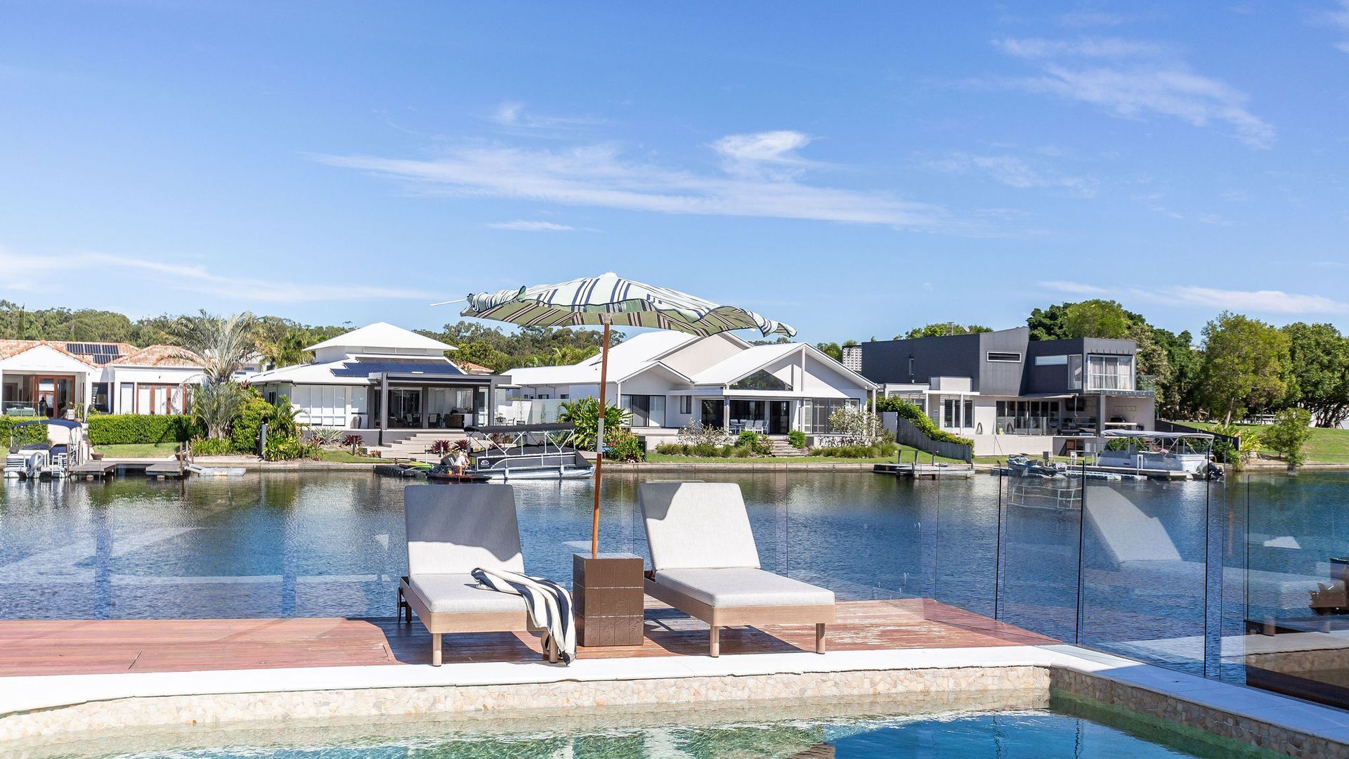 A residential area with a swimming pool, modern houses, and a large umbrella.