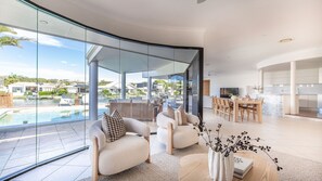 Ein modernes Wohnzimmer mit Glaswand, Pool und Essbereich.