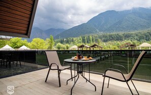 Una terraza con mesa y sillas, con vista a un paisaje montañoso.