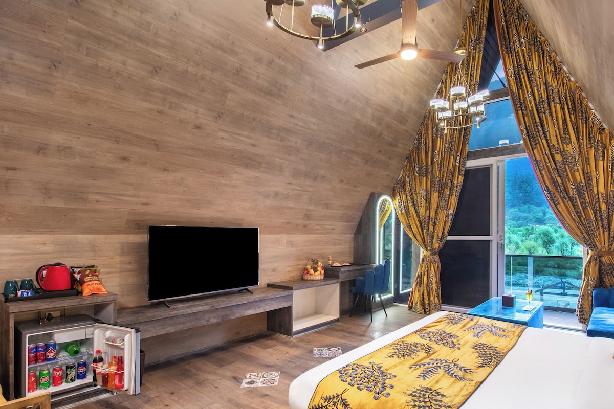 Un dormitorio con cama, televisor, refrigerador pequeño y balcón con vistas.