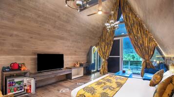 Un dormitorio con cama, televisor, refrigerador pequeño y balcón con vistas.