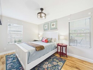 A bedroom with a bed, bedside tables, a ceiling fan, and a window with blinds.