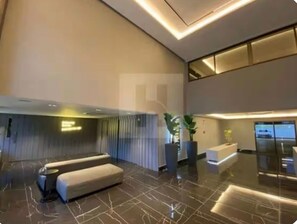 Eine moderne Lobby mit einer Rezeption, einer Sitzecke und einem großen Fenster.