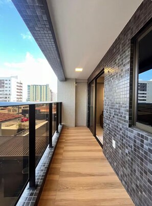 Ein Balkon mit Holzboden, gefliesten Wänden und Blick auf die Stadtlandschaft.