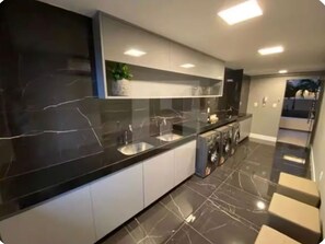 Eine moderne Küche mit schwarzem Marmorarbeitsplatz, integrierten Geräten und einer weißen Spritzschutzwand.
