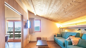 A wooden ceiling, a sofa, a television, and a view of mountains. - Chic Duplex Apartment in Doucy (La Léchère)