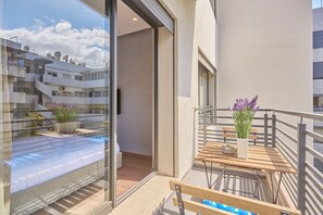 Eine moderne Wohnung mit Balkon, Blick auf benachbarte Gebäude und einem Blumentopf.