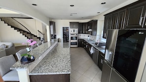 A modern kitchen with granite countertops, stainless steel appliances, and dark cabinetry.
