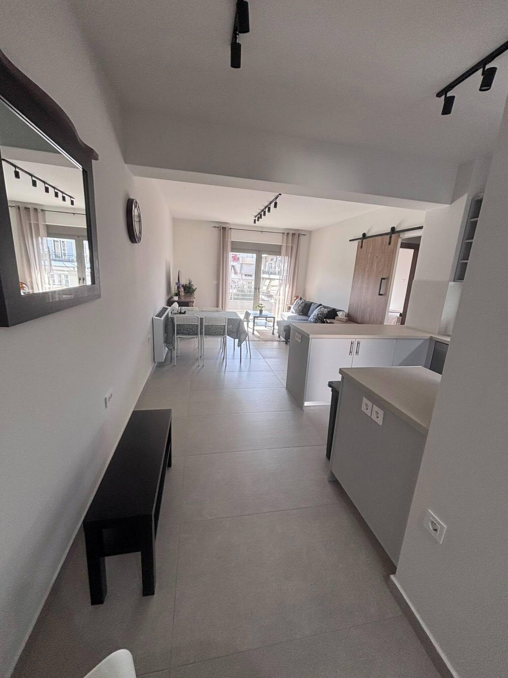 A modern apartment with a dining area, kitchenette, and a bench.