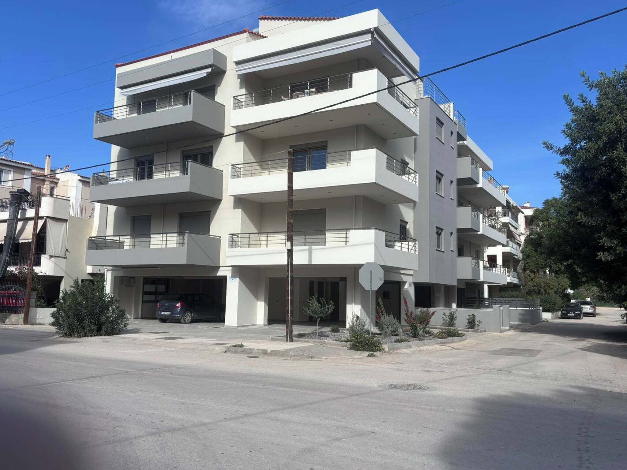 A multi-story residential building with balconies, a garage, and a clear sky.