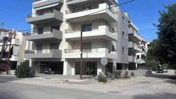 A multi-story residential building with balconies, a garage, and a clear sky.
