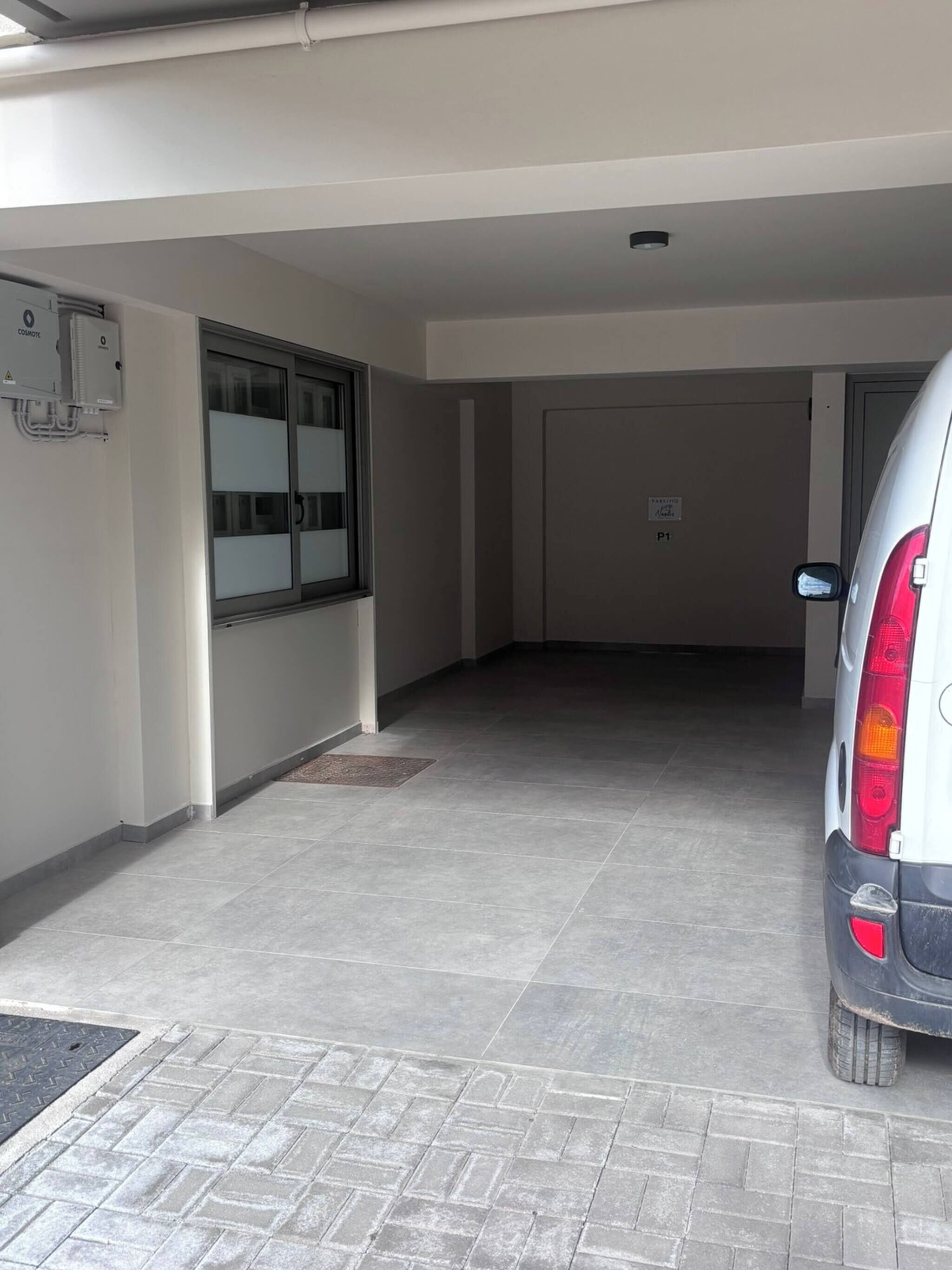 A parking garage with a white car, a window with frosted glass, and a door marked 'P1'.