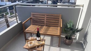 A wooden bench with a bottle of wine, two glasses, and a tray with snacks on a balcony. - Vasili's Mini Villa in Nafplio With Shaded Parking (Nafplio)