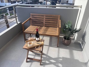 A wooden bench with a bottle of wine, two glasses, and a tray with snacks on a balcony. - Vasili's Mini Villa in Nafplio With Shaded Parking (Nafplio)