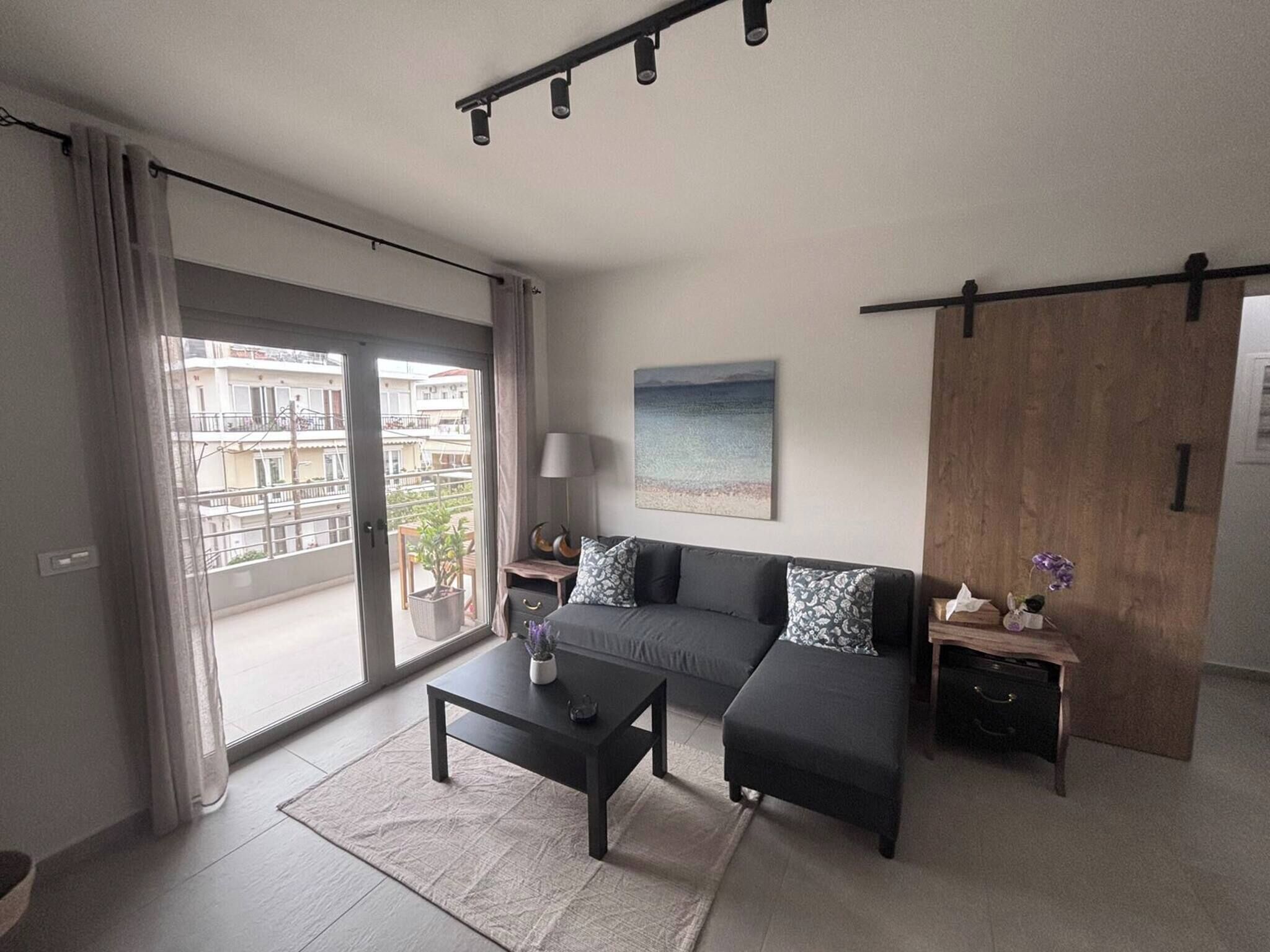 A modern living room with a sofa, coffee table, and a view of a balcony.