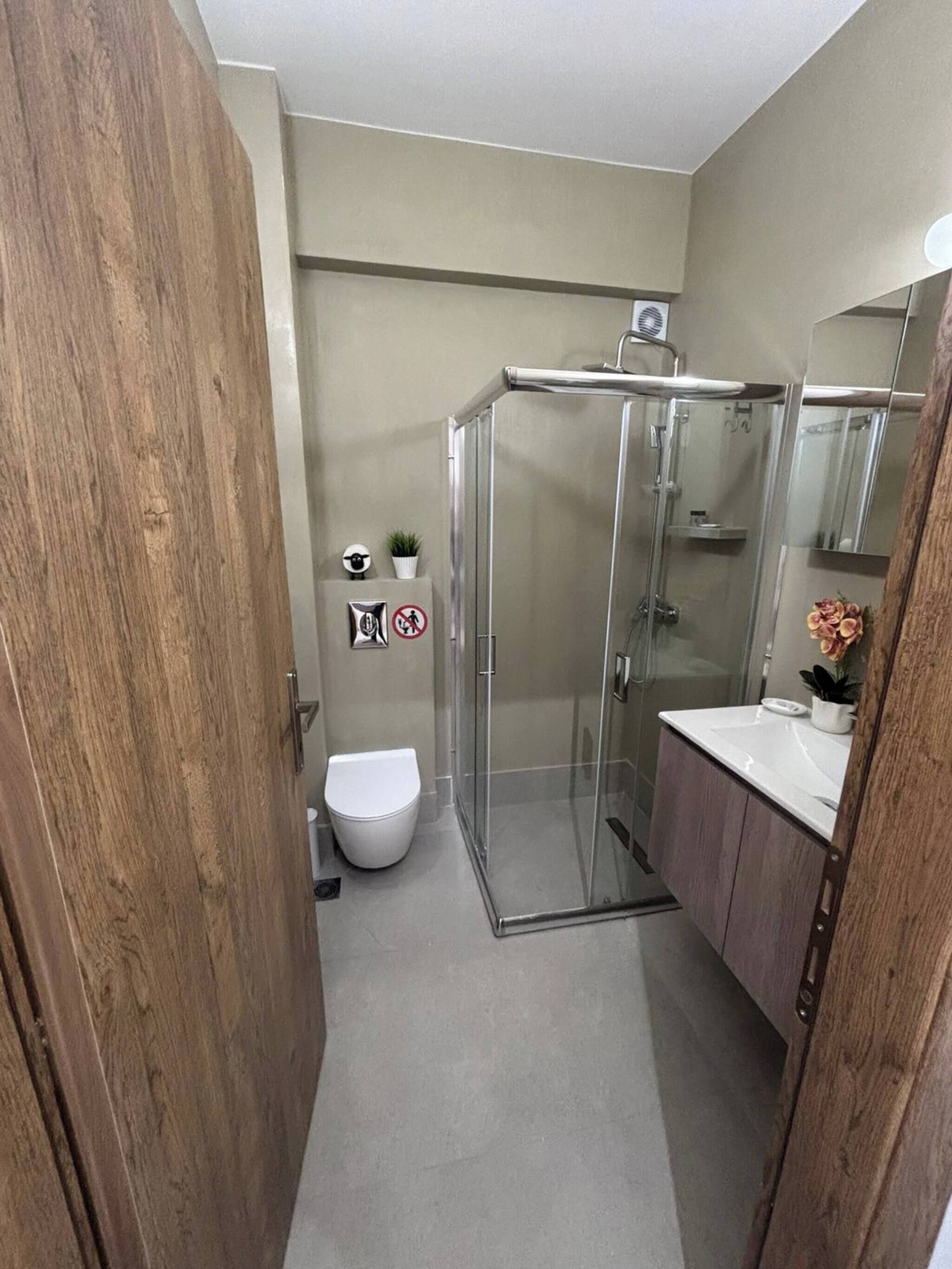 Une salle de bain avec une douche à parois de verre, des toilettes et un lavabo avec un miroir.