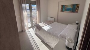 A hotel room with a bed, a window with curtains, a radiator, and a painting on the wall. - Vasili's Mini Villa in Nafplio With Shaded Parking (Nafplio)