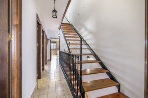 Un escalier avec des marches en bois et des rampes noires, menant à l’étage supérieur.