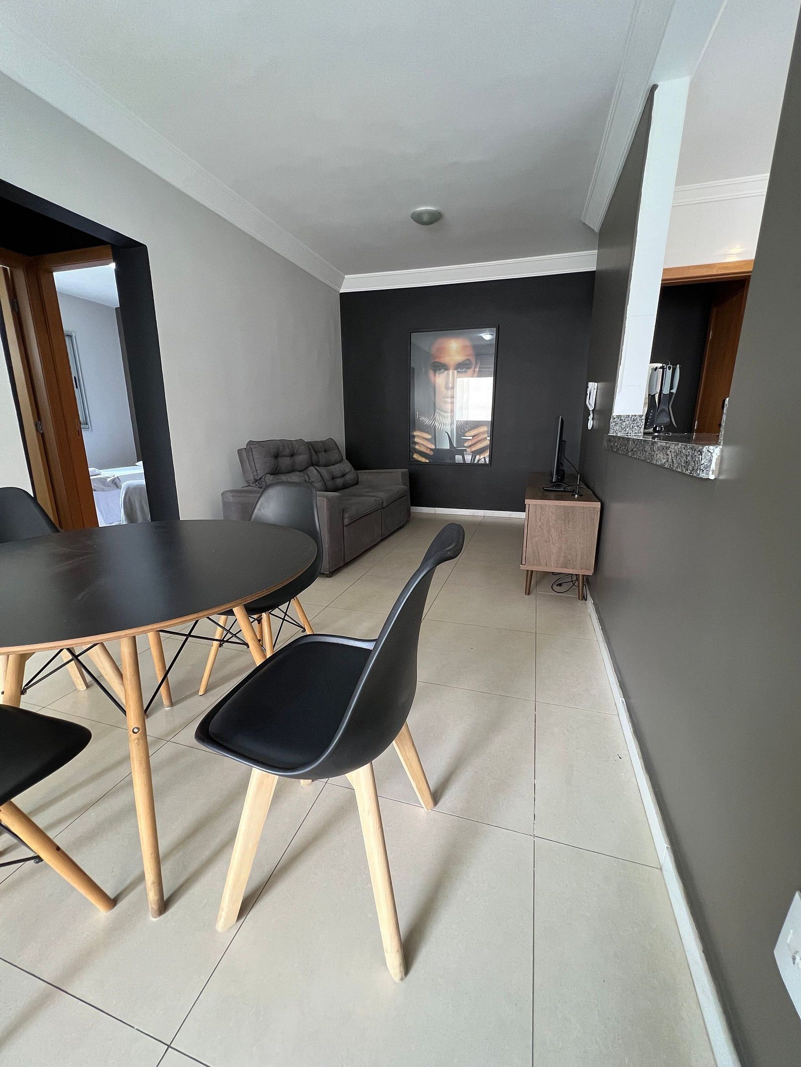 A modern living room with a dining table, chairs, a sofa, and a TV.